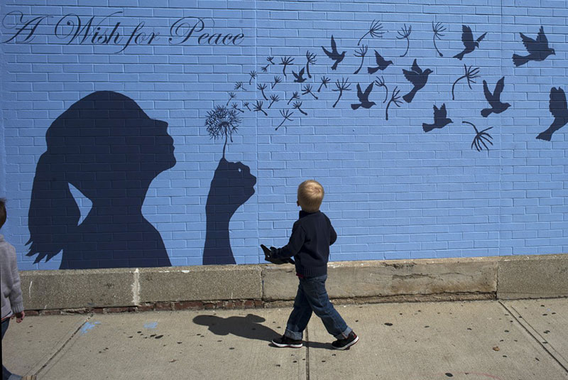 a-boy-looks-up-at-a-mural-reading-a-wish-for-peace-in-medford-massachusetts-september-15-2014