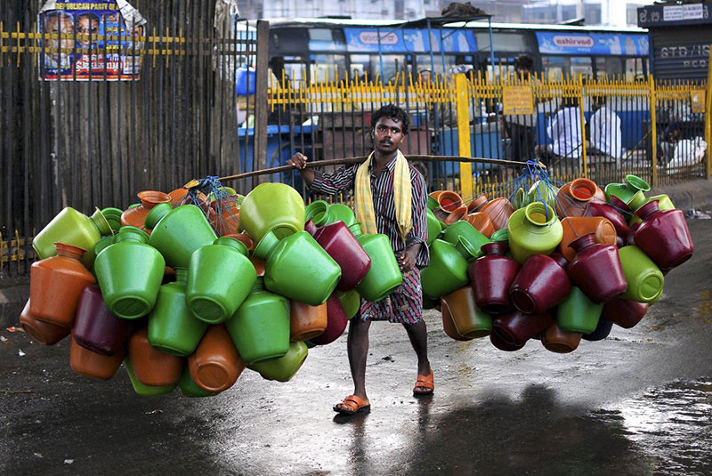 a-man-carries-empty-water-pitchers-for-sale-in-a-market-in-the-southern-indian-city-of-bangalore-on-october-9-2014