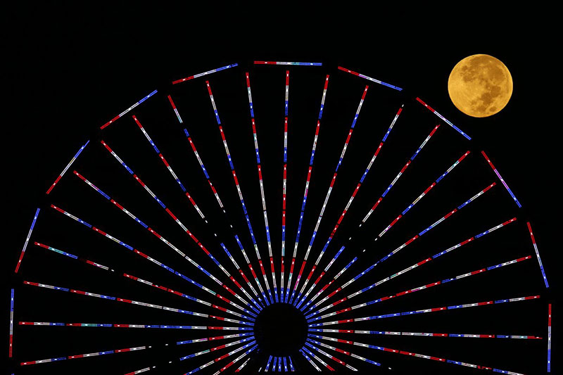 the-moon-is-pictured-behind-a-ferris-wheel-on-the-pier-in-santa-monica-california-after-a-total-lunar-eclipse-also-known-as-a-blood-moon